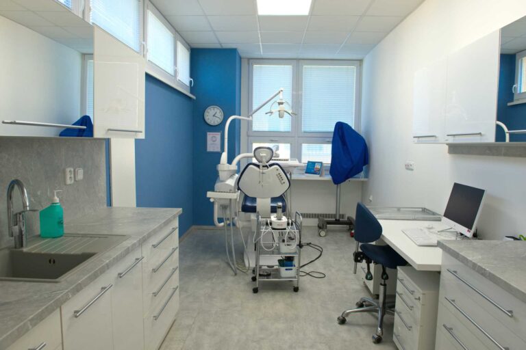 Prostorná zubní ordinace s modrým křeslem.